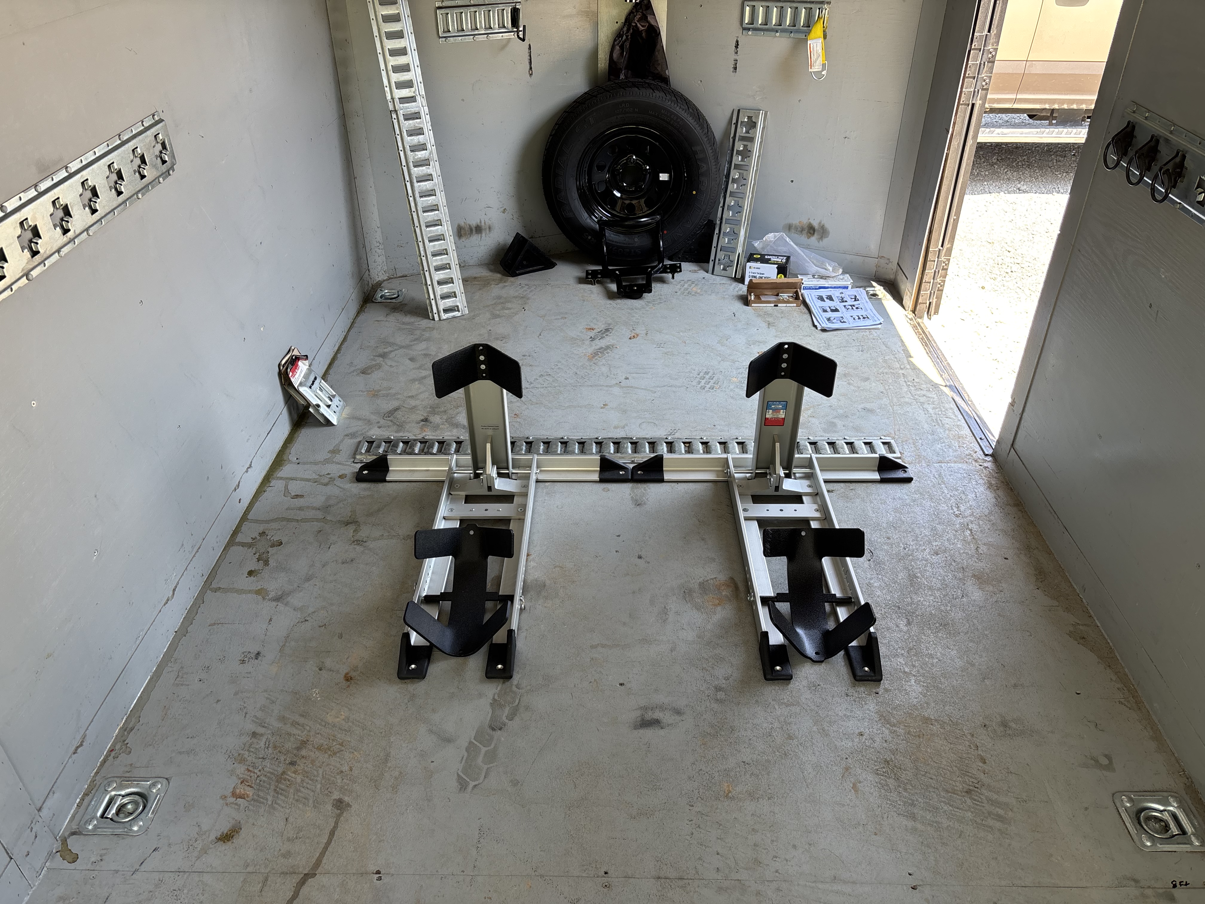 Professional motorcycle wheel chock systems set up in trailer interior with tie-down tracks